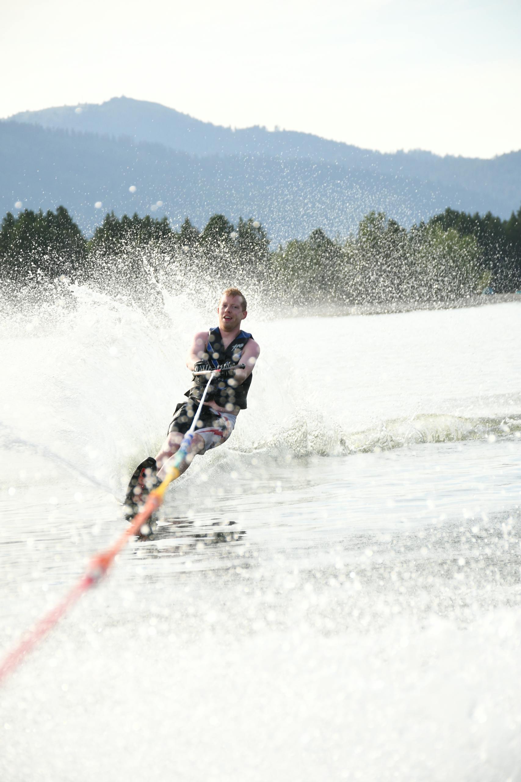 Excited sportsman practicing slalom water skiing on splashing ocean