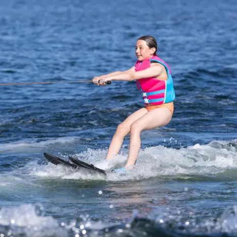 Obrien All Star Trainer Waterskis Lifestyle 04 Child riding O'Brien All-Star Trainer Waterskis while holding tow rope on open water.