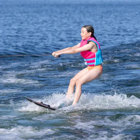 Obrien All Star Trainer Waterskis Lifestyle 05 Side view of child riding O'Brien All-Star Trainer Waterskis while holding tow rope on open water.