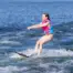 Side view of child riding O'Brien All-Star Trainer Waterskis while holding tow rope on open water.