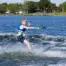 Action shot of a child waterskiing and giving a thumbs-up on O'Brien Celebrity 58" combo waterskis.