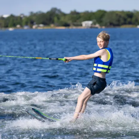 Obrien Celebrity 58 Combo Waterskis Lifestyle 05 Action side view of a child gliding on O'Brien Celebrity 58" combo waterskis across small wake.