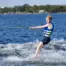 Action side view of a child gliding on O'Brien Celebrity 58" combo waterskis across small wake.