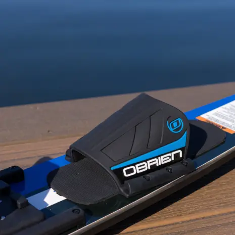 Obrien Celebrity 68 Combo Waterskis Detail 04 Close-up of a black and blue O'Brien ski boot binding on a ski with a blurred water background