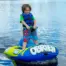 Child using the O'Brien Simple Trainer Inflatable Ski on a calm lake.