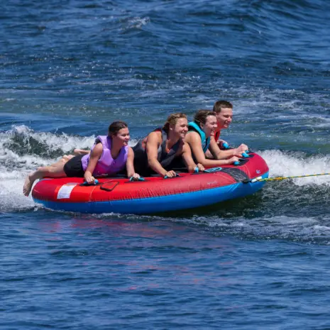 Obrien X Scream Boat Tube Lifestyle 05 Four people on a red and blue X-Scream towable tube in the water.