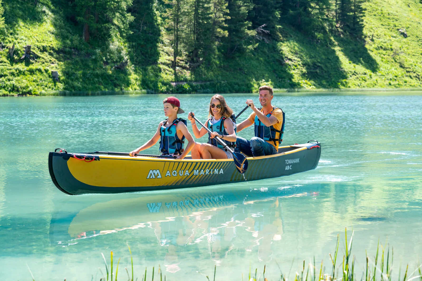 Family paddling an Aqua Marina Tomahawk Air-C on a calm alpine lake