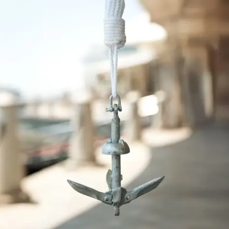 Aqua Marina anchor kit - folding anchor hanging from a white rope outdoors Aqua Marina anchor kit - folding anchor hanging from a white rope outdoors