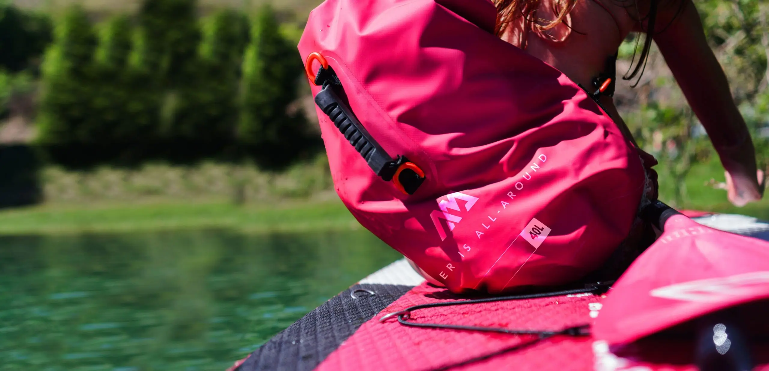 Aqua Marina Pink 40L Dry Bag 1 Aqua Marina pink 40L dry bag - pink dry bag carried beside a paddle board on the water