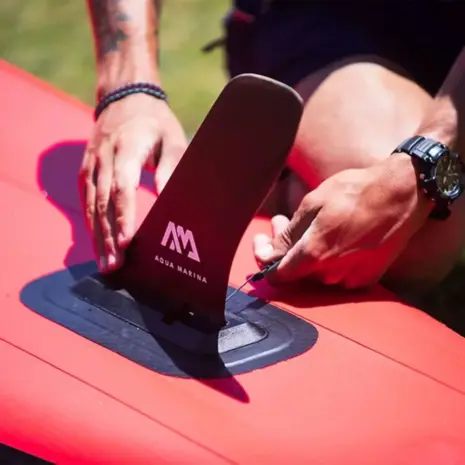 Aqua Marina slide-in racing fin - person fitting a pink fin to a paddle board Aqua Marina slide-in racing fin - person fitting a pink fin to a paddle board